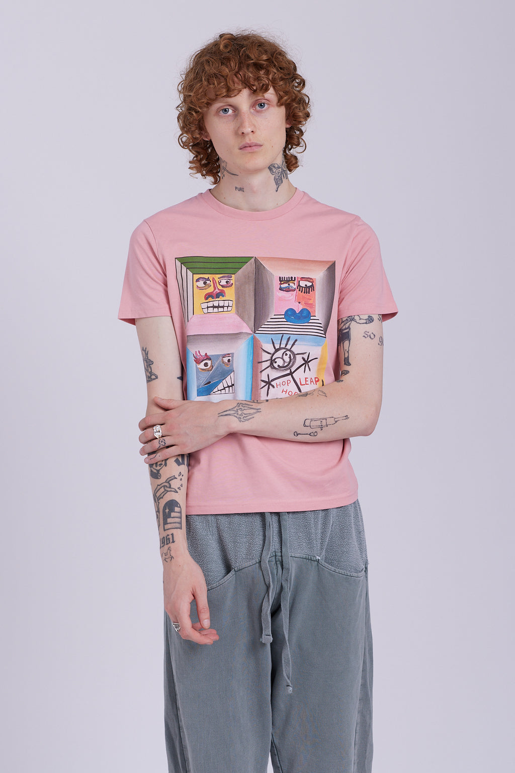 An organic cotton t-shirt in rose clay color with a graphic print of four different characters in a grid layout. Four Moods affirmation tee — rose clay organic cotton t-shirt with painted mood print, unisex fit, mental health charity